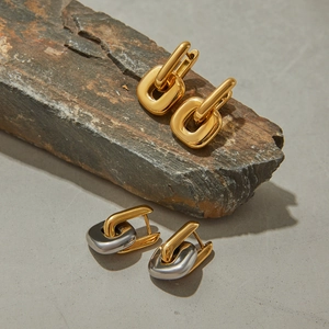 Polished bicolor and gold interlocking geometric earrings on a natural grey rock surface