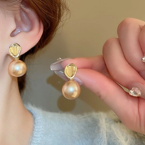 Gros plan sur d'élégantes boucles d'oreilles papillon dorées avec perles champagne