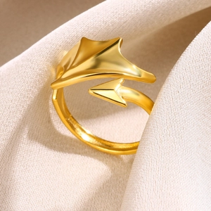 Detail of a golden wing and arrow open ring on soft beige textured fabric background
