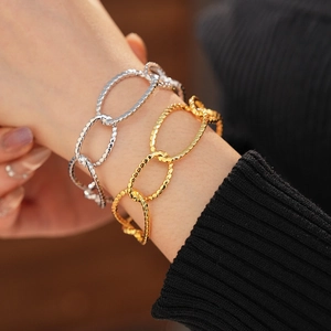 Detail of gold and silver chunky chain bracelets with textured hammered finish on a wrist