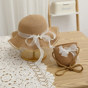 Detail of straw hat and matching bag set with white lace bows and pearl accents