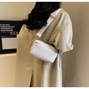 Detail of off-white PU leather crossbody bag with geometric pattern wide strap on model