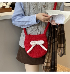 Detail of red plush crossbody bag featuring a white fluffy bow and lamb wool texture