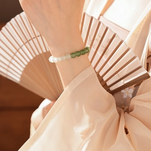Elegant jade and chalcedony beaded bracelet worn with a traditional Chinese folding fan
