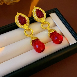 Detailed macro view of vintage gold flower earrings with red teardrop gems and small crystals