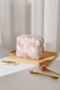 Detail of pink bow and floral print cotton cosmetic bag on a wooden tray decor