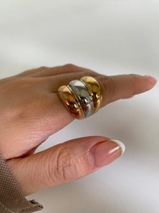 Detail of a wide triple-band ring in gold, silver and rose gold on a finger