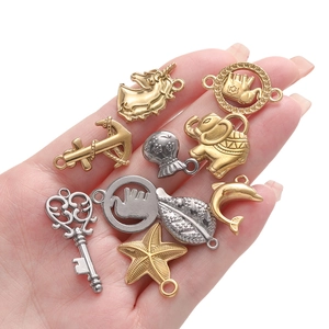 Assorted gold and silver stainless steel ocean charms including starfish and shells on a hand