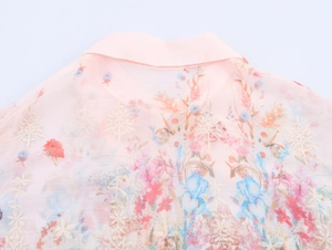 Detail of floral embroidery and print on a sweet pink chiffon puff sleeve shirt collar