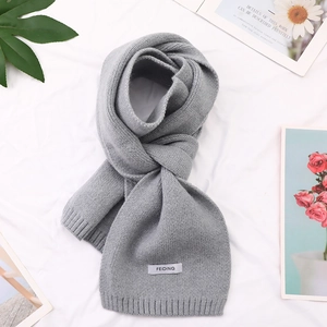Detail of light grey knit scarf showing fine ribbed edges and white textile label