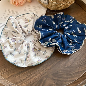 Close-up of two floral scrunchies with rabbit patterns on a wooden tray with decor