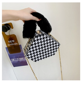 Detail of houndstooth hexagonal handbag with black plush handle and gold chain strap
