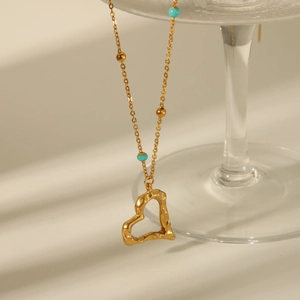 Vintage 18K gold-plated heart necklace with turquoise beads on a glass edge