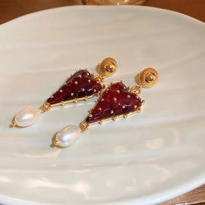 Détail de boucles d'oreilles cœur vintage avec émail rouge et perles blanches pendantes