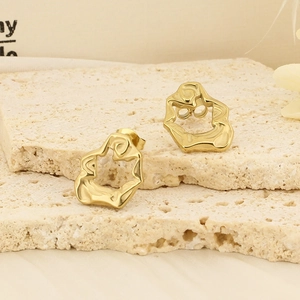 Vue détaillée de boucles d'oreilles dorées géométriques sur une surface en pierre beige