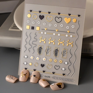 Macro view of 3D embossed nail stickers featuring gold heart and balloon dog designs