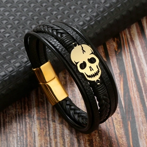 Close-up of black braided leather multi-layer bracelet with golden skull and magnetic clasp