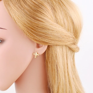 Detailed close-up of a golden airplane stud earring with micro-inlaid white crystals