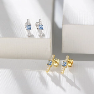 Macro shot of silver stud earrings featuring square blue zircon and S925 hallmark engraving