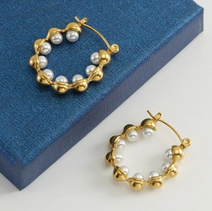 Detail of 18k gold plated hoop earrings with wavy texture and white pearls