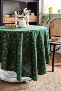 Detail of green Christmas tablecloth with gold snowflakes and bell prints on cotton linen
