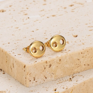Polished gold coffee bean stud earrings on natural stone stairs in a luxury setting