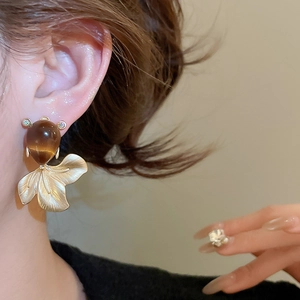 Close-up of matte gold goldfish earrings with brown resin stone on model's ear