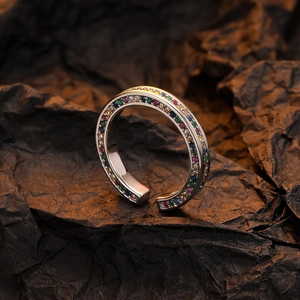 Elegant silver open ring with colorful zircon stones on a dark textured background