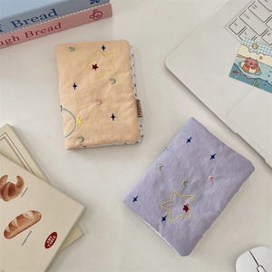 Detail of embroidered star and moon fabric passport covers in orange and purple