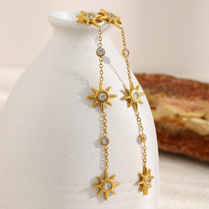 Elegant 18K gold plated starburst dangle earrings with sparkling zircon on a white vase