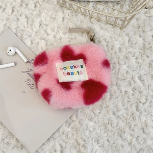 Detail view of pink plush heart coin purse with red cow pattern and white woven label