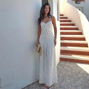 Abito lungo bianco a pois con scollo all'americana in un ambiente esterno curato