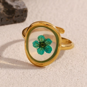 Detail shot of green dried flower embedded in clear resin with an 18K gold stainless steel ring