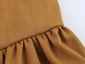 Vue macro montrant la texture du tissu plissé marron et les détails de couture de la robe