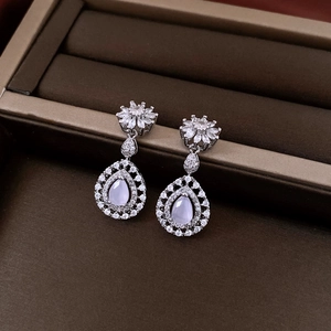 Detailed macro view of pear-cut drop earrings with zircon floral accents in a jewelry box