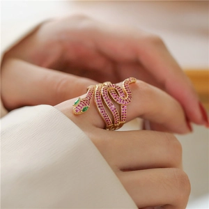 Detailed close-up of a snake-shaped open ring with pink zircon and green gem eyes