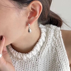 Classic silver teardrop earrings with a mirror-polished finish worn by a fashion model