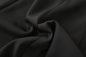Close-up of black sleeveless midi dress showing fine twill fabric texture and soft drapes
