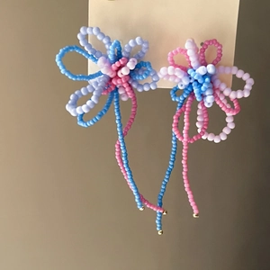 Detailed view of handmade beaded flower tassel earrings in pastel blue pink and purple