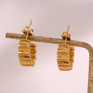 Vue détaillée de boucles d'oreilles créoles C dorées en acier avec texture ondulée