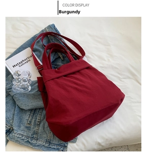 Detail view of a wine red lightweight nylon tote bag on a casual white fabric surface