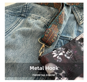 Detailed shot of golden metal hook with colorful bohemian strap and skull print fabric
