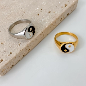 Tai Chi Yin Yang stainless steel rings in gold and silver finishes on stone background