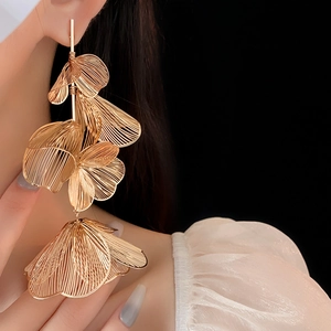Macro detail of gold-tone layered flower petals earrings in an elegant hollow design