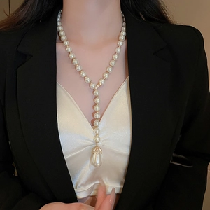Detailed view of a Y-shaped pearl necklace with a teardrop pendant on a female model