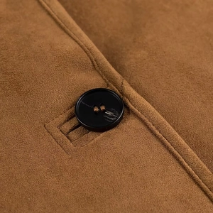 Close-up of a black button and suede texture on a brown faux shearling jacket