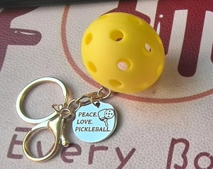 Detail of yellow pickleball keychain with engraved Peace Love Pickleball metal tag