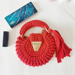 Bohemian red crochet round shoulder bag with tassel and gold clasp on white background