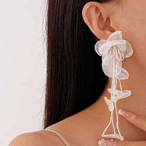 Detail of white tulle flower earrings with long beaded tassels and silver needles
