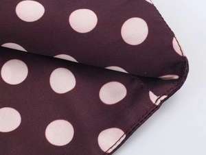 Makroaufnahme von Polka-Dot-Muster auf weinrotem Gewebe mit feiner Nahtführung